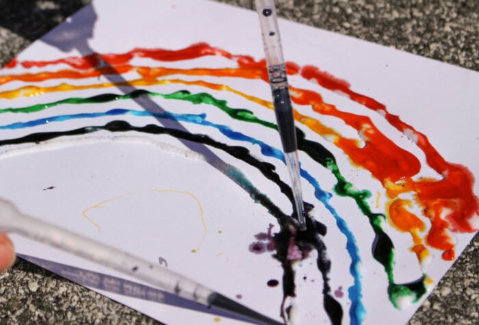 Bright Rainbow Salt Painting for Preschoolers 12 pipette filled with purple water dripping onto rainbow salt painting activity