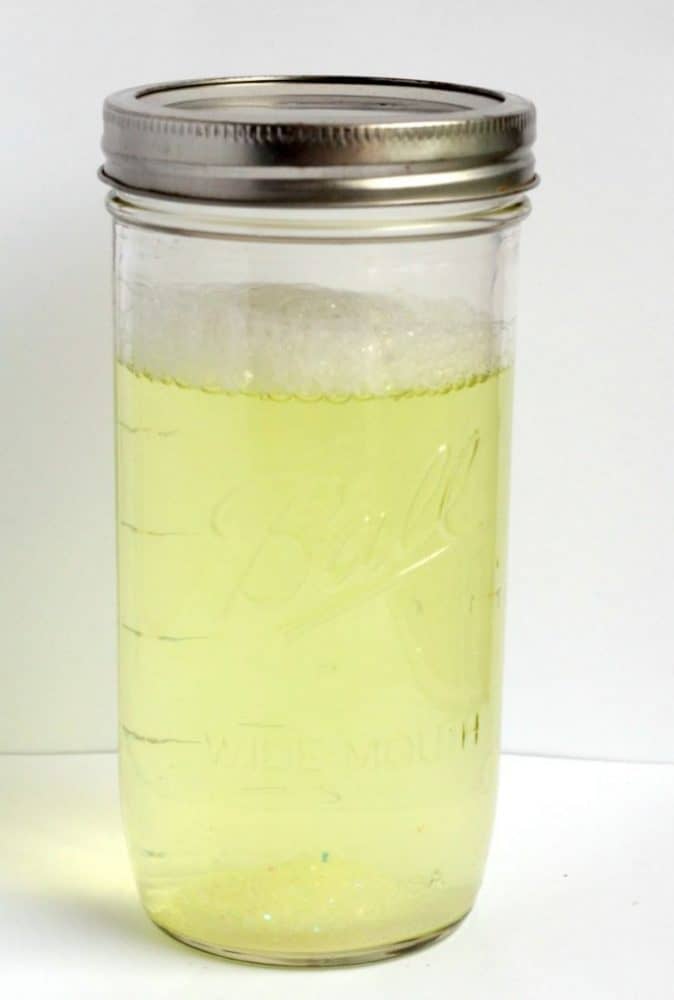 Tornado in a Jar: Simple Science Experiment for Kids 7 up close image of a tall mason jar filled with soapy water.