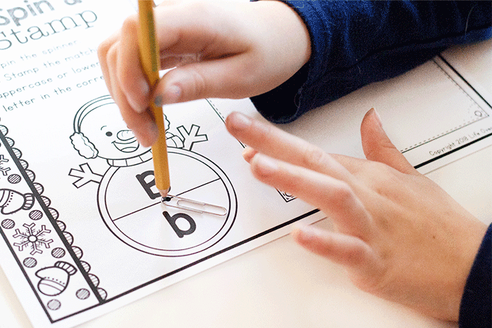 a child using the "spinner" for the letter "b" snowman spin & stamp alphabet activity worksheet.