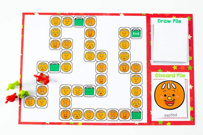 Free Printable Gingerbread Emotions Board Game for Kids 13 overhead image of the ginger bread theme emotions game with plastic people figures as game markers and a card showing an excited gingerbread face.