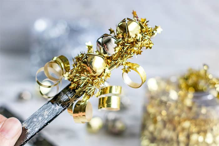 use bells, popsicle sticks and ribbon to create a simple diy new years eve noise maker for kids
