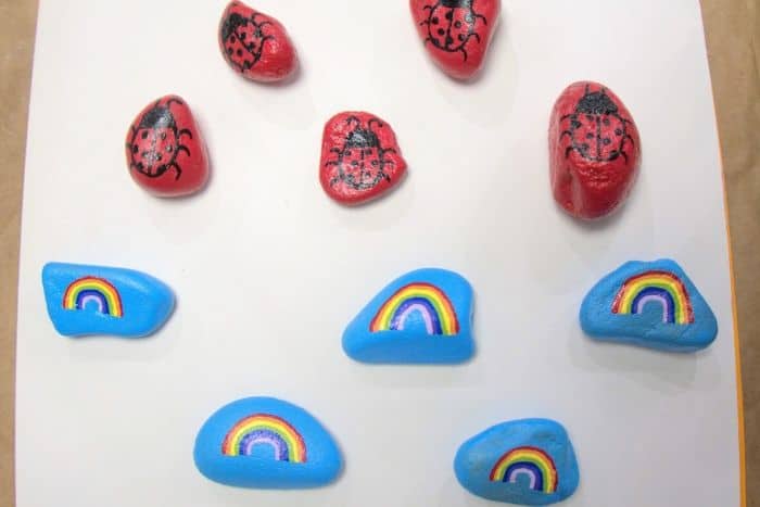 five small blue rocks with little rainbows painted on them and five red rocks with little ladybugs painted on them.