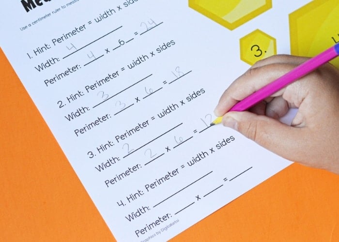 hand writing with a pencil on a bee math worksheet.