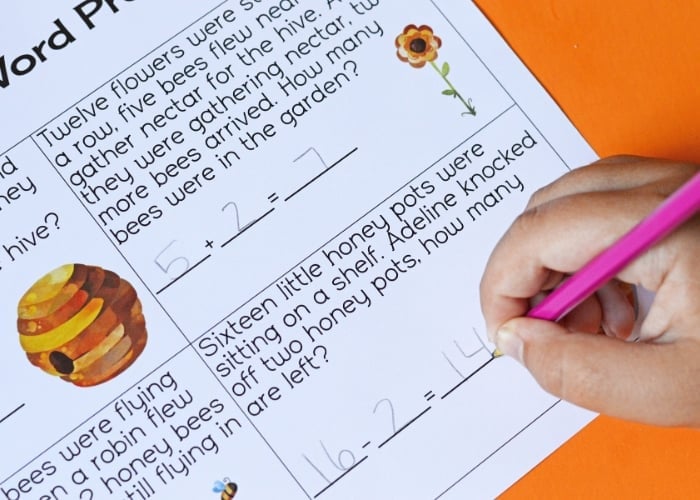 hand writing the answer to a bee math word problem on a worksheet.