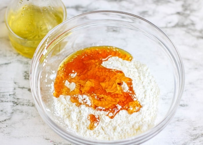 honey and dry ingredients in a clear mixing bowl for making slime.