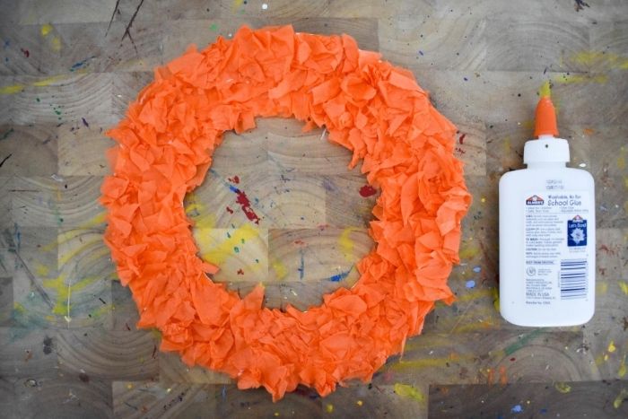 a paper plat wreath form cover in tiny pieces of orange tissue paper.