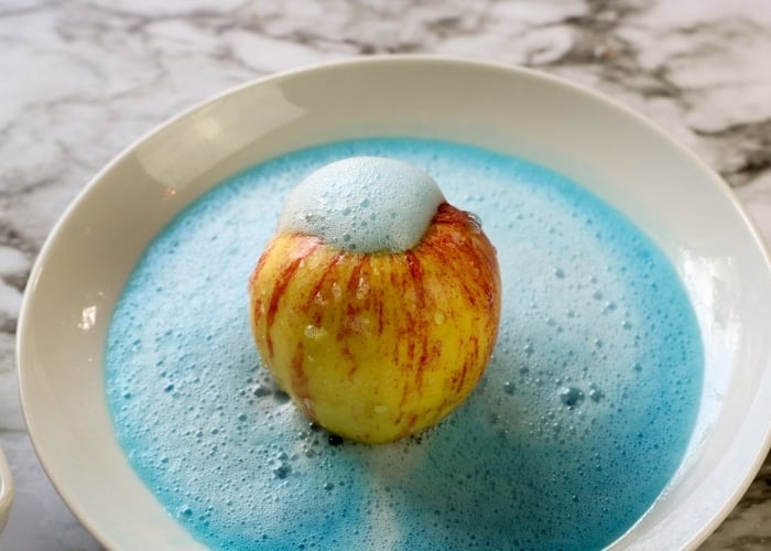 overhead shot of the apple volcano science experiment with blue food coloring.