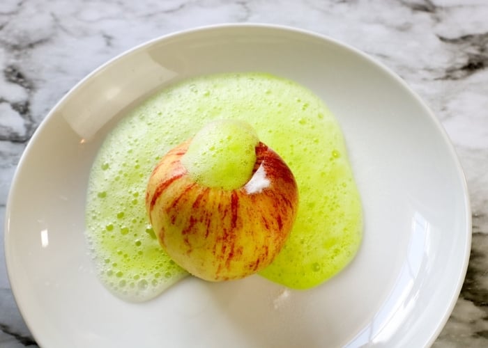 overhead shot of the apple volcano science experiment with green food coloring.