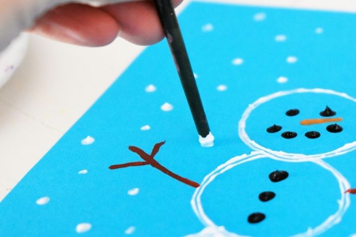 a hand painting snowflakes on the easy diy snowman craft.