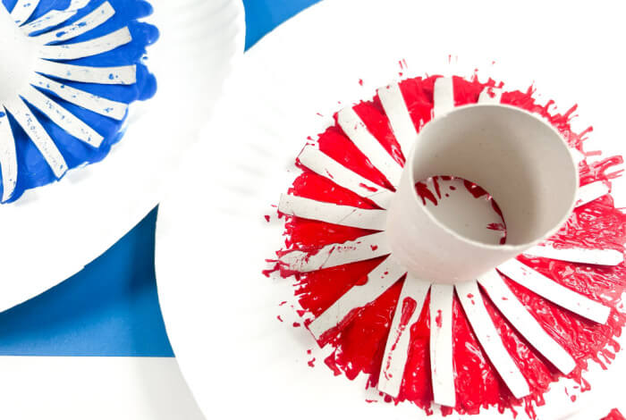 press the toilet paper tubes into the red and blue paint so that all the strips are covered in paint.