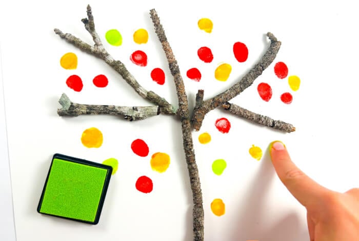 colorful fingerprints make the leaves on the fall tree craft.