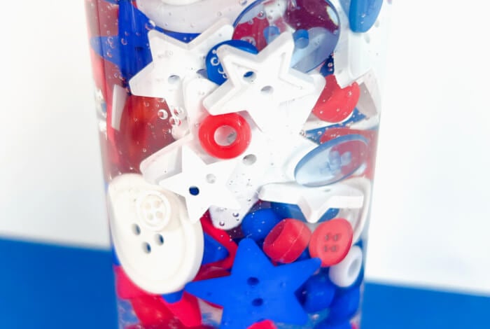 close up shot of red, white, and blue buttons and beads inside of a sensory bottle.