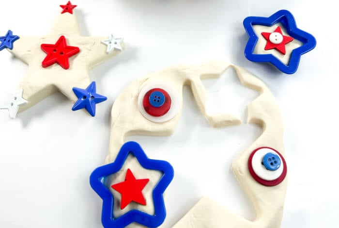 overhead image of someone cutting star shapes out of play dough for a july 4th activity.