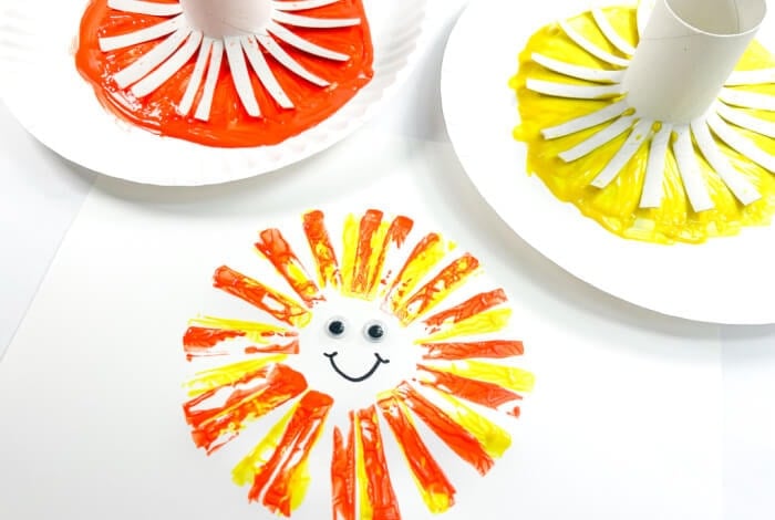 a finished sunshine made from a toilet paper roll, orange paint, yellow paint, googly eyes, and a marker.