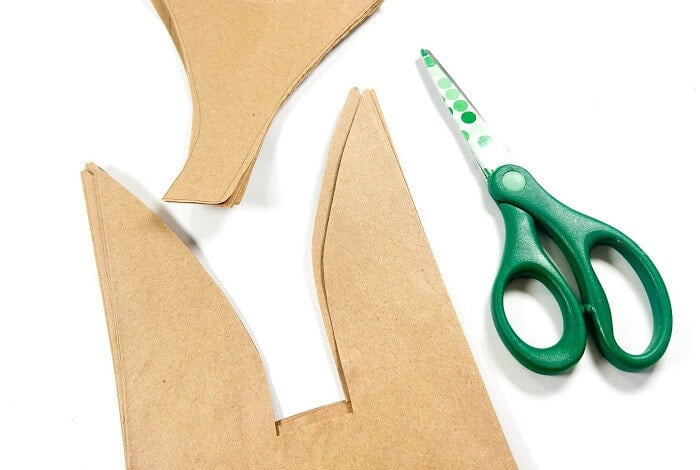 Easy & Adorable Easter Bunny Paper Bag Craft 13 a pair of scissors cutting the ears out of a brown paper bag.