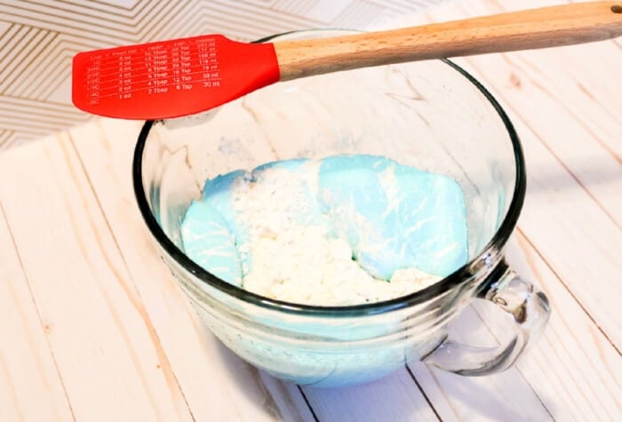 overhead shot of a spatula resting on a glass mixing bowl full of a taste safe play dough mixture.