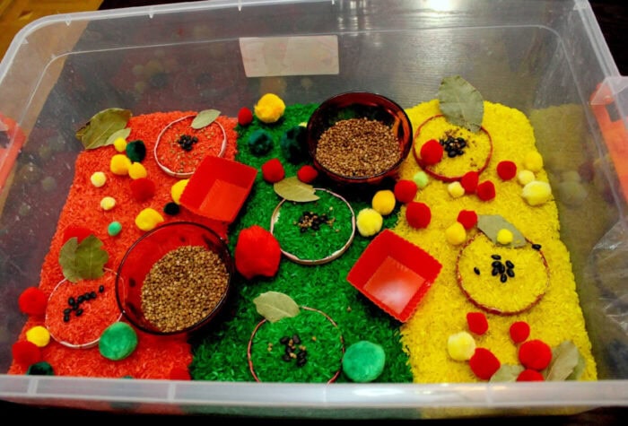 overhead view of an apple sensory bin made with dyed rice.