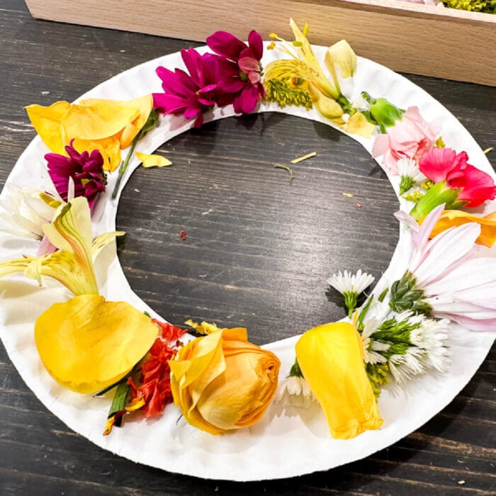 a finished wreath craft with colorful flowers glued to the paper plate.