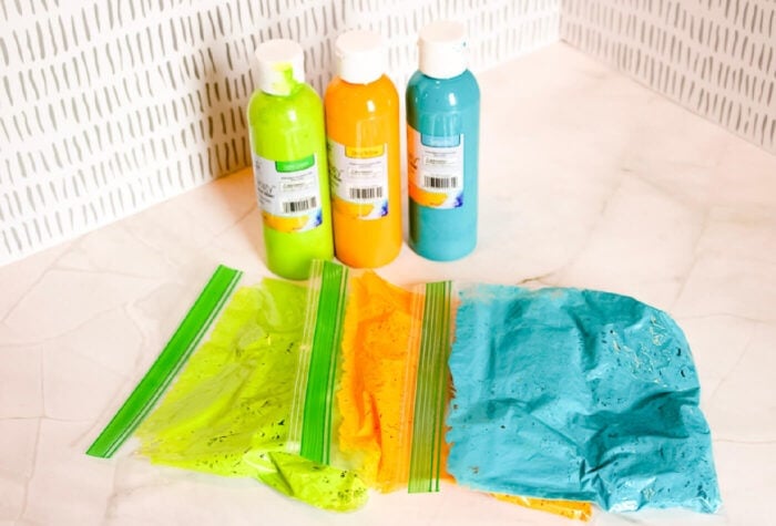 three baggies full of painted pasta are laying on a counter.