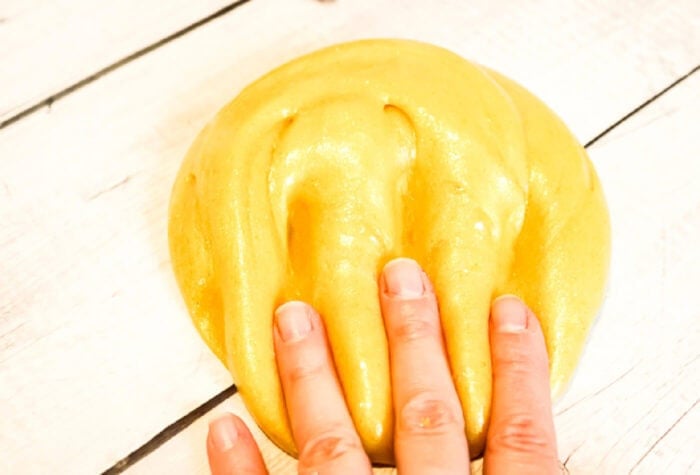 someone putting their hand in a ball of golden slime.