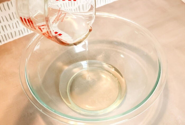 someone is pouring water into a glass bowl.