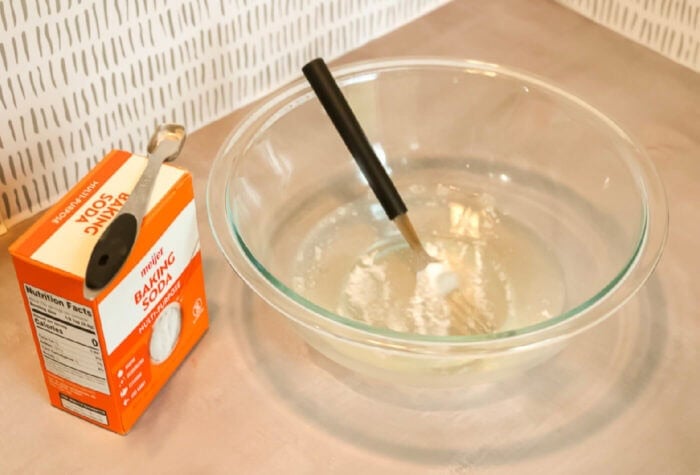 How to Make Golden Slime for Kids 20 someone is adding baking soda to a mixture of water and clear glue.