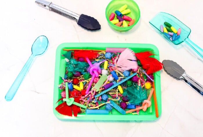 overhead view of a sensory bin made with colorful non-food items.