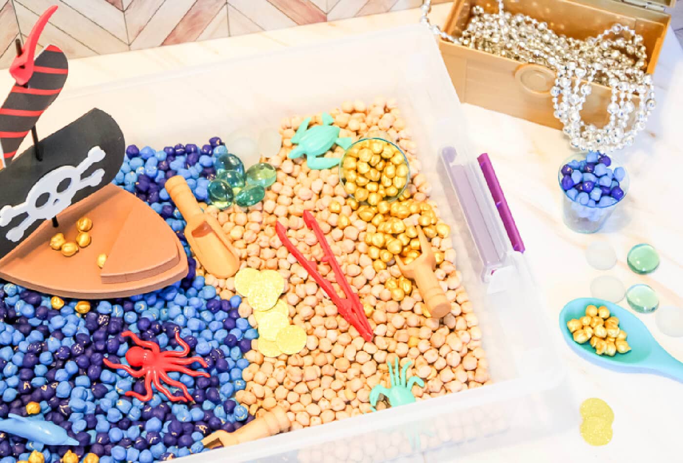 overhead view of pirate theme accessories inside a chickpea sensory bin.