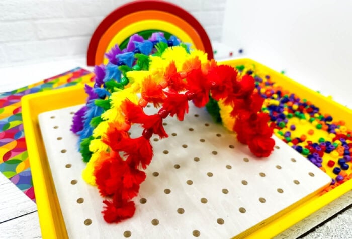rainbow colored pipe cleaners are poked through a pegboard to create a pipe cleaner rainbow.