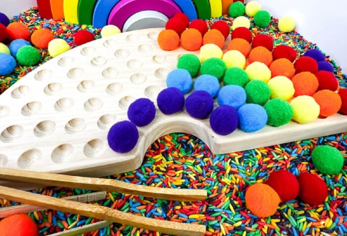 placing pom poms in the wooden holder to create a rainbow.