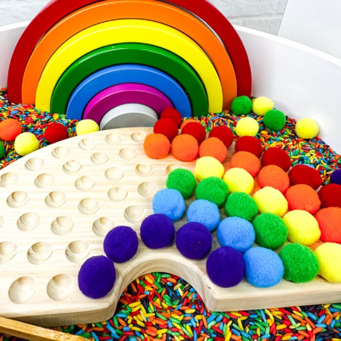 playing with the wooden rainbow puzzle inside the rainbow sensory bin.