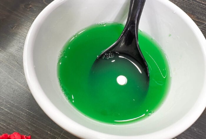How to Make Spring Flower Ooblek for Kids 15 overhead shot of green liquid inside a white bowl.