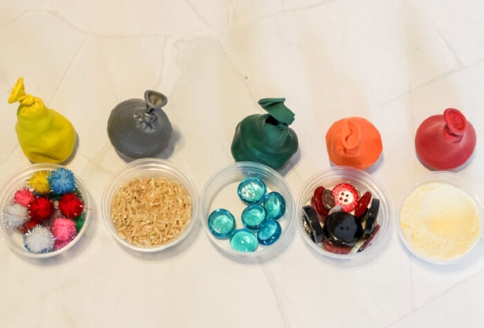 overhead shot of five sensory balloons and five bowls filled with materials to go inside the balloons.