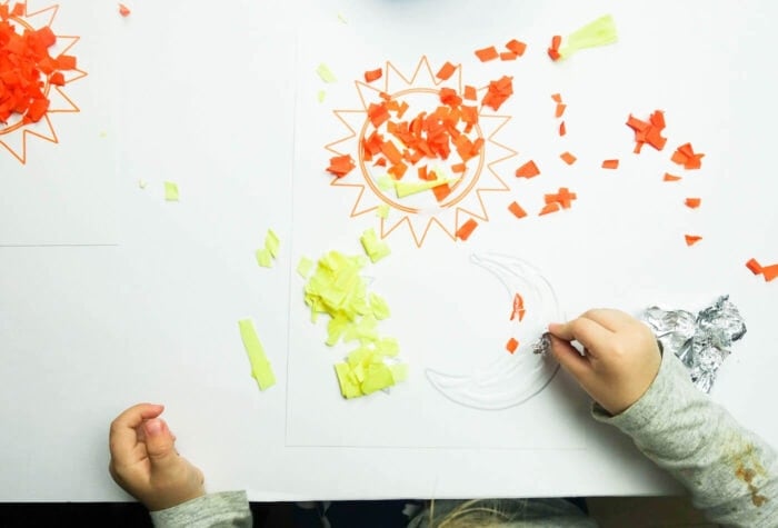 Exciting Outer Space Theme Lesson Plans for Preschool 16 a child is using pieces of torn paper to fill in the outline of a sun and moon.