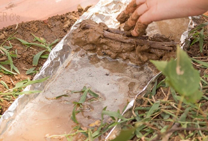 Fun, Hands-On River Small World Habitat Exploration 17 a child is placing sticks in mud to make a dam in a river sensory bin.