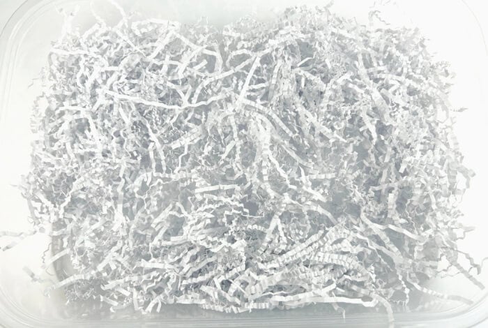white shredded paper is in the bottom of a plastic bin.