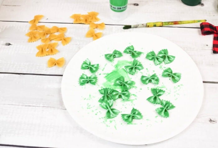 photo of farfalle pasta painted green on a white paper plate