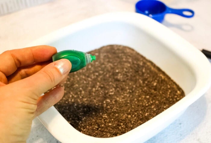 someone is adding drops of green food coloring to a mixture of chia seeds and water.