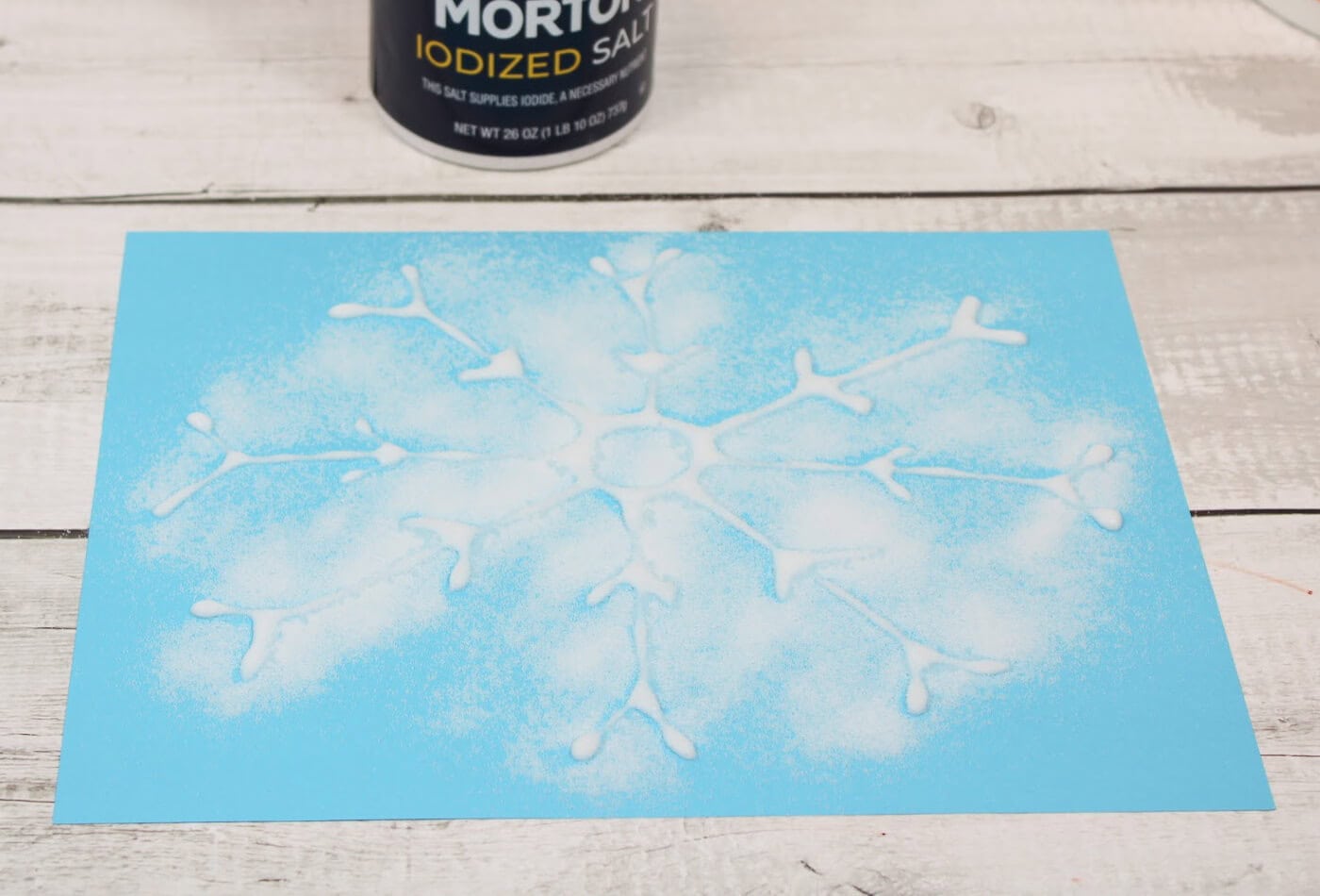 Easy Winter Salt Painting Art Activity for Kids 15 overhead image of salt shaken out on a piece of blue paper.