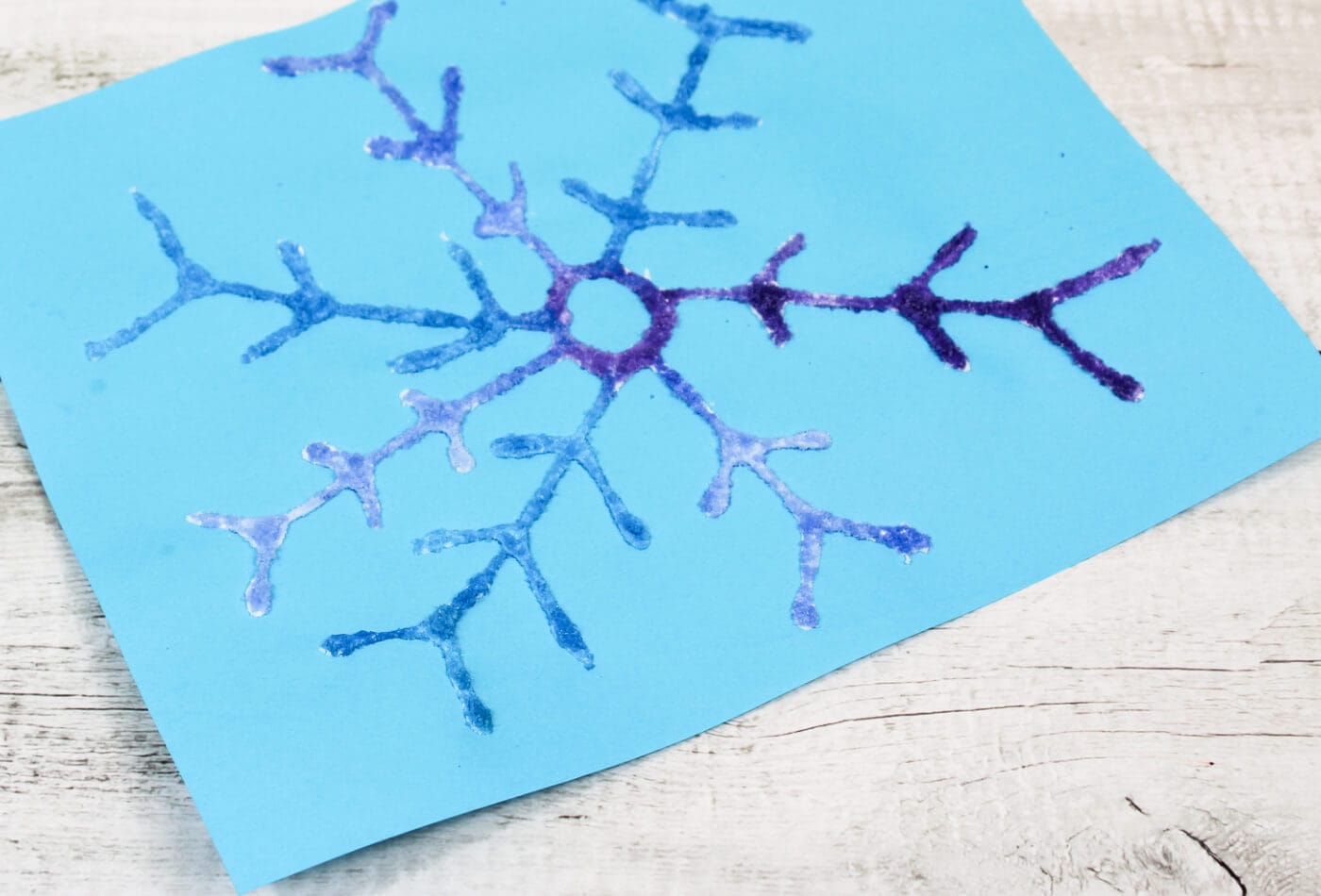 Overhead image of a blue and purple snowflake salt painting.