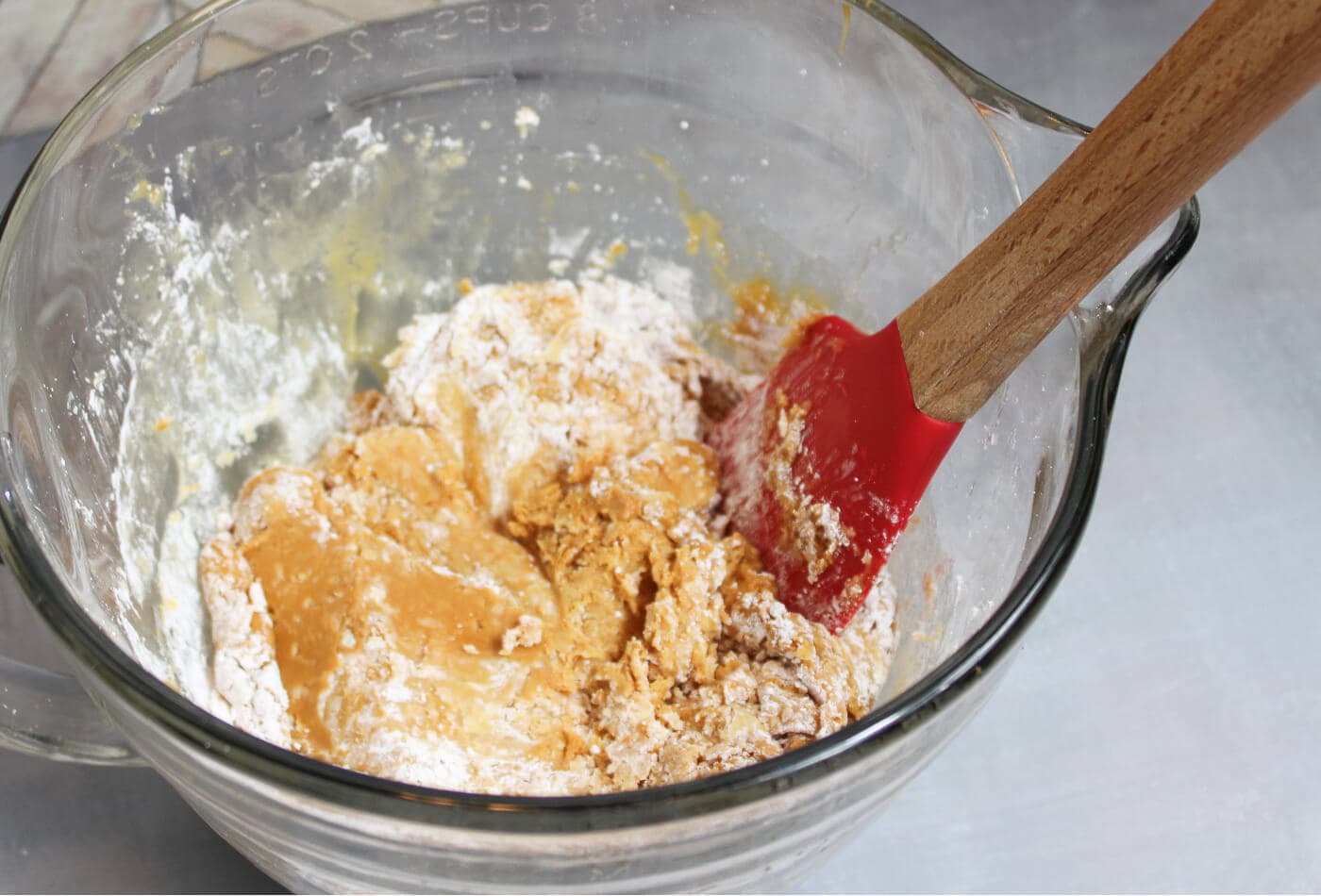 wow butter and honey combined in a glass mixing bowl before adding powdered sugar to make peanut-free, taste-safe play dough for preschool sensory play.