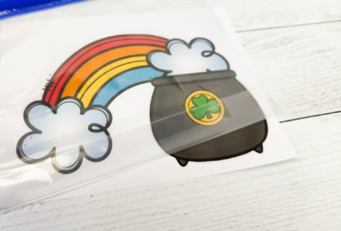 placing a zip top bag onto a printed pot of gold counting mat to create a st. patrick's day sensory bag counting activity