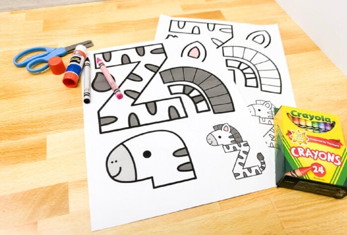 free printable uppercase letter z craft template for preschoolers with zebra parts ready to color, cut, and assemble. includes crayons, scissors, and glue stick on a wooden table.