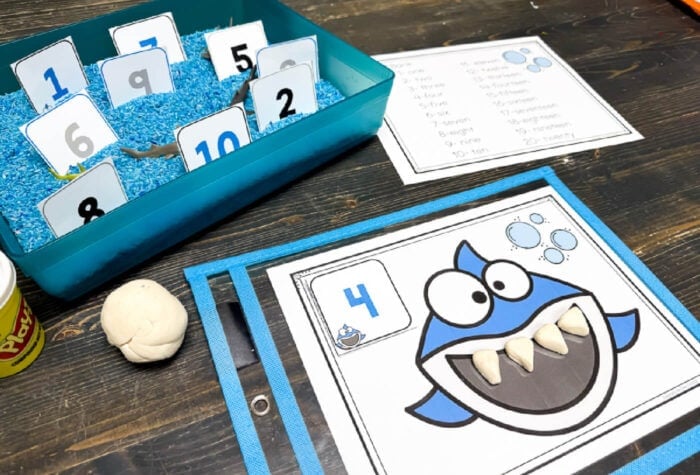 preschooler pressing play dough teeth onto a printable shark math mat while practicing counting and building finger strength.