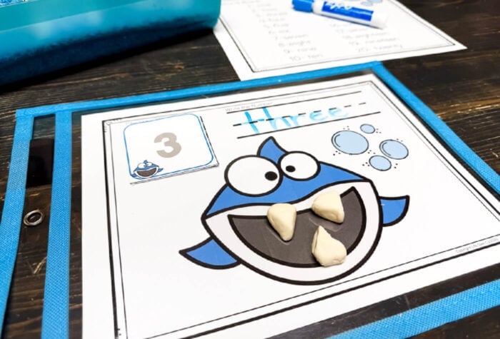 interactive preschool counting mat with ocean-themed shark, number card, and space for kids to place matching play dough teeth