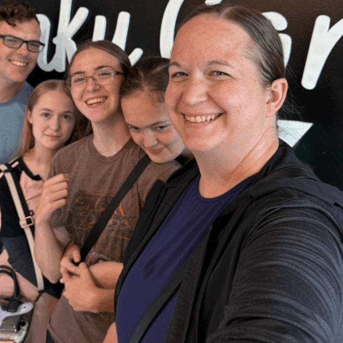 life over c’s creator smiling for a casual family selfie with her husband and three daughters, creating a friendly, personal introduction to the educator and family behind life over c’s.